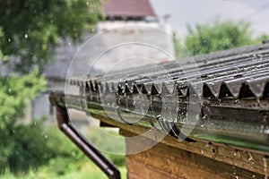 Streams of rain are flowing down from the roof.