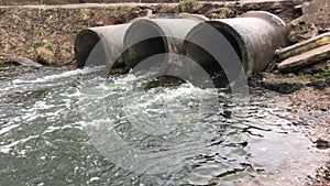 Streams of water flow through concrete sewers. Polluted body of water in the park