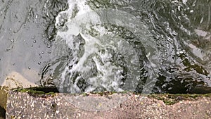 Streams of water flow through concrete sewers. Polluted body of water in the park. Close-up shot from above