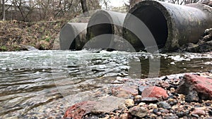 Streams of water flow through concrete sewers. Polluted body of water in the park. Shooting from the water level