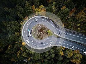 Street from above trough a misty forest at autumn, aerial view flying through the clouds with fog and trees