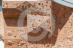 Street artificial rock climbing wall close-up view various colored grips. Colorful footholds for training. Orange climbing wall