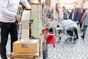 Street artist busker man playing music by organ barrel vintage wooden box machine at crowded old european city France