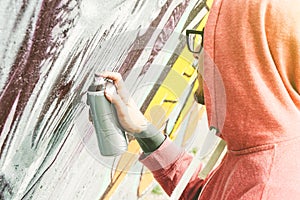 Street artist painting graffiti with color spray his art on the wall - Young man writing and drawing murales on the street photo