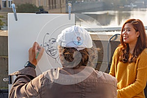 Street artist paints a beautiful girl in Prague