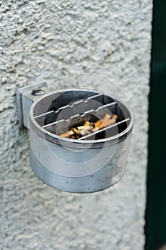 Metal ashtray on a wall full with cigarette old retro style not cleaned