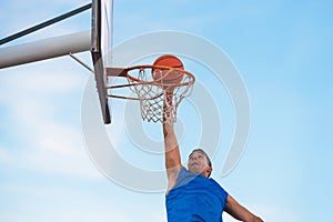 Street basketball athlete performing slam dunk on the court