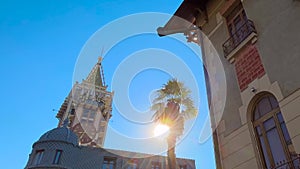 Street of Batumi with clock tower, palm tree and old building - sun lens flares
