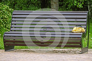 Street bench with a forgotten woman\'s handbag at the edge