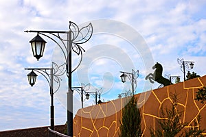 Street beutiful vintage lamps aligned with beautiful blue sky with white clouds on background and horse figure