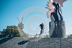 Street biker with a bike practicing free style and jumping at t