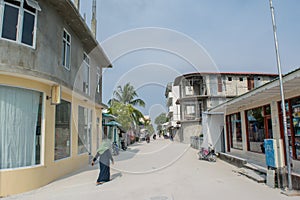 Street with buildings, bikes and people during sunny day at the tropical island Maamigili