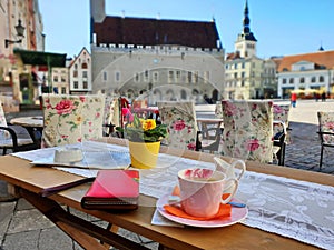 Street Cafe in the city on table cup of coffee with flowers and red ladies wallet sunshine day blue sky cityscape lifestyle