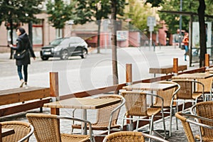 A street cafe in Prague in the Czech Republic. In the foreground there are empty wooden tables and wicker chairs. City