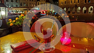 Street cafe table with glass of tea candle light flowers city lamp light red green colored town of Tallinn ,Estonia 20,