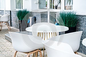 Street cafe with white chairs, green foliage around. Without people, tourism, travel.