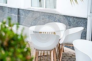 Street cafe with white chairs, green foliage around. Without people, tourism, travel.