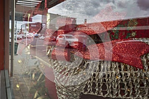 Street and cars reflected in shop window with Christmas decoration. Auckland