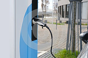 street, charging with electricity through cable, electric vehicle in European city, eMobility charging,energy accumulators, photo