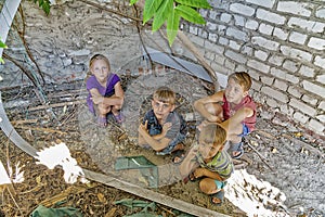 Street children sit in the trash in the corner of an abandoned house. Staged photo