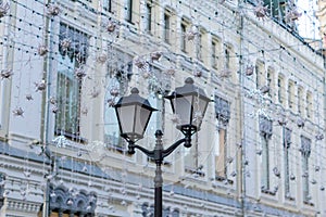 Street christmas decoration. White garlands above the street and vintage street lantern