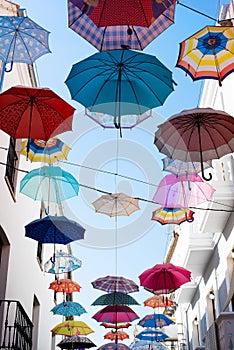 Street decorated with umbrellas of different colors. Concept of umbrellas sky