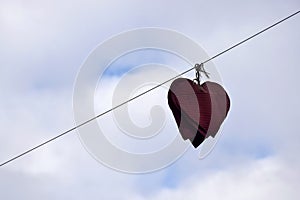 Street decoration. Several handmade red metal hearts hang on wire against cloudy sky. Valentine\'s Day Concept. Copy space.