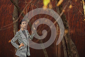 Street fashion concept. Fashion portrait of beautiful brunette in trendy casual clothes posing in autumn park over rusty metal