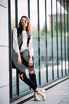 Street fashion concept - pretty young slim woman in rock black style posing against the wall