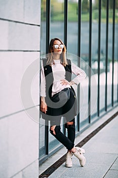 Street fashion concept - pretty young slim woman in rock black style posing against the wall