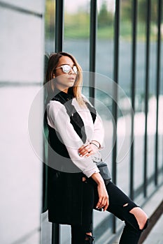 Street fashion concept - pretty young slim woman in rock black style posing against the wall