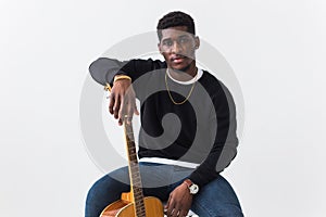 Street fashion concept - Studio shot of young handsome African man wearing sweatshirt with guitar against white