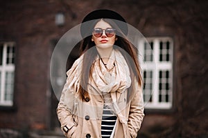Street fashion concept. Vintage portrait of young woman in spring coat and hat. Flattering hair photo