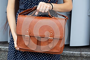 Street fashion concept. Woman holding brown leather briefcase. Space for text