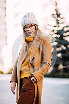 Street fashion concept. Young beautiful model in the city. Beautiful blonde woman Model wearing mustard sweater, beige coat and