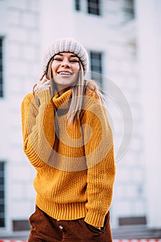 Street fashion concept. Young beautiful model in the city. Beautiful blonde woman Model wearing mustard sweater, and stylish