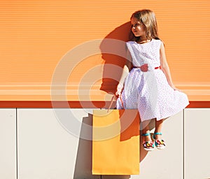 Street fashion kid, pretty little girl in dress with shop bag