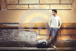 Street fashion model tourist man outdoor. Waiting on grunge wall