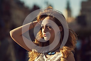 Street fashion portrait of a young beautiful happy lady posing on the urban background. Model looking aside. Girl