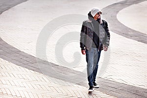 Street fashion, stylish african american man wearing black leather jacket, hoodie, sneakers, jeans, beanie and