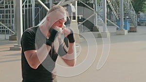 Street fighter boxing in punching bag outdoors