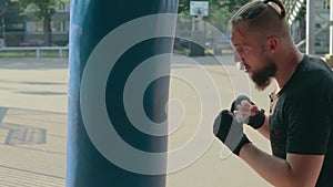 Street fighter boxing in punching bag outdoors
