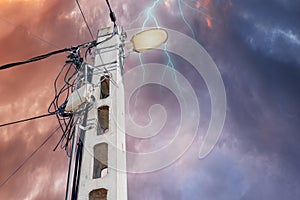 Street flood light post with many wires against dark stormy cloudy dramatic sky  background. With space for text.