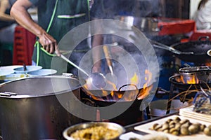 Street food in Bangkok Bangkok Thailand - Oct 24, 2020 :- Chef cooking with fire with frying pan on gas hob