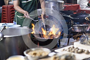 Street food in Bangkok Bangkok Thailand  Chef cooking with fire with frying pan on gas hob at yoawarat Bangkok