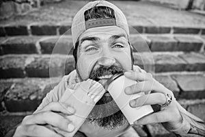 Street food concept. Man bearded eat tasty sausage and drink paper cup. Urban lifestyle nutrition. Junk food. Carefree