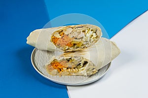 Street food donner sandwich wrapped in lavash bread served on plate on blue and white abstract background