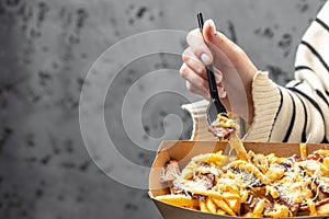 Street food plate with french fries. Female hands holding box tasty fried potatoes with beef stew and mayonnaise