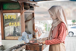 street food seller with walking stall of indonesian Chicken Satay Cooking on a Hot Charcoal Grill