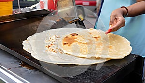 A street food vendor expertly flipping parathas